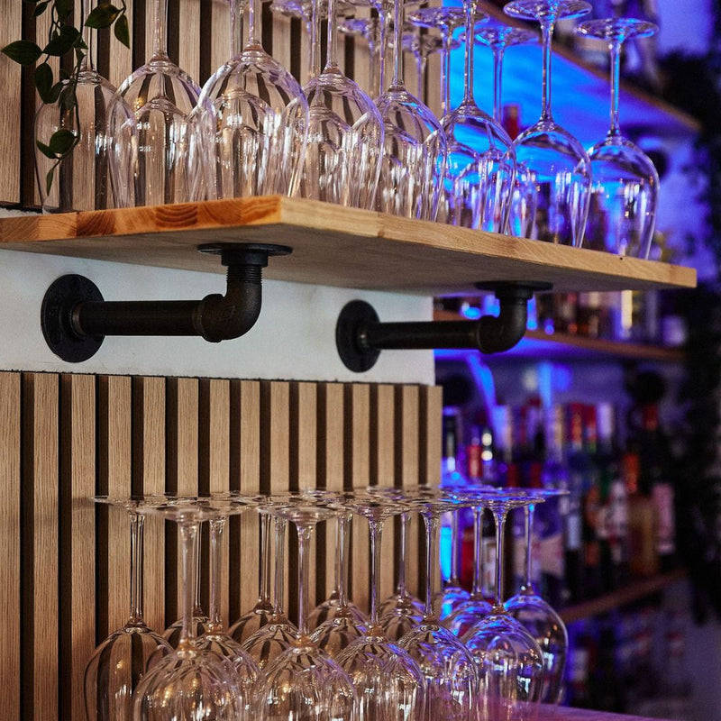 wall mounted shelves made from industrial dark iron supports with oak shelf for glasses in bar