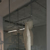 silver clothes rack made from water pipes attached to ceiling to hang jackets in entrance