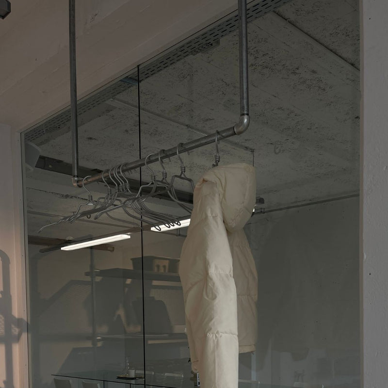 silver clothes rack made from water pipes attached to ceiling to hang jackets in entrance