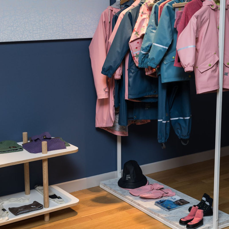 Free standing clothes rack in kids store for rain clothes with white rust free rail and marble plate