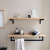 Modern bathroom set up with floating shelves made from oak and special metal rail to hang towels