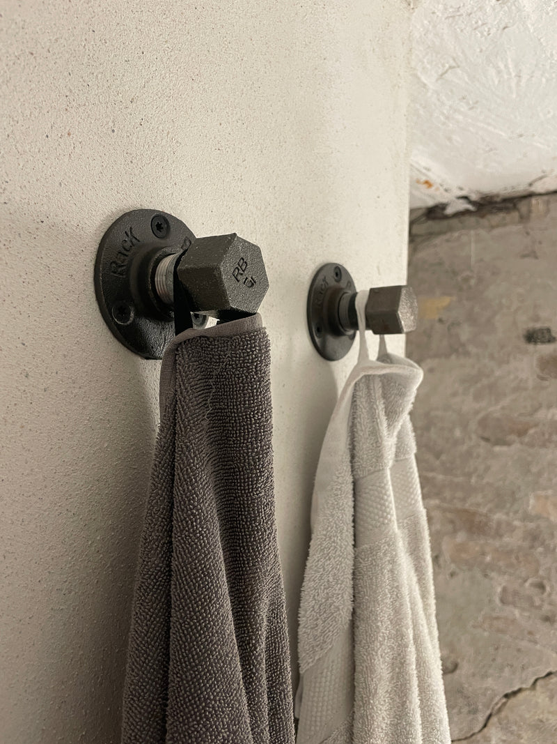 Wall mounted clothes hooks made from dark water pipes to hang towels in the bathroom