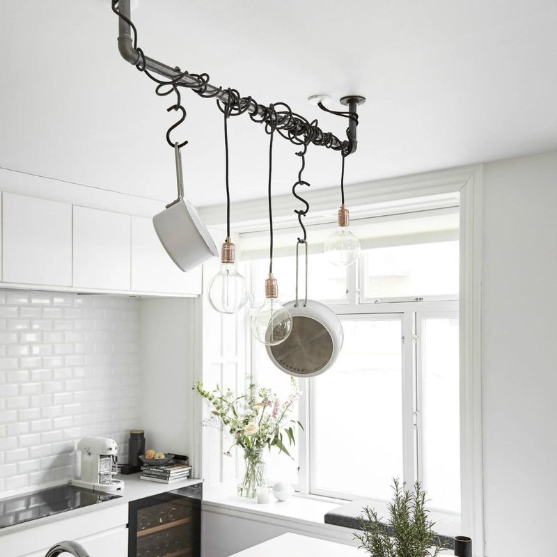 ceiling mounted rail made from dark water pipes to hang pots and pans and light blubs in kitchen