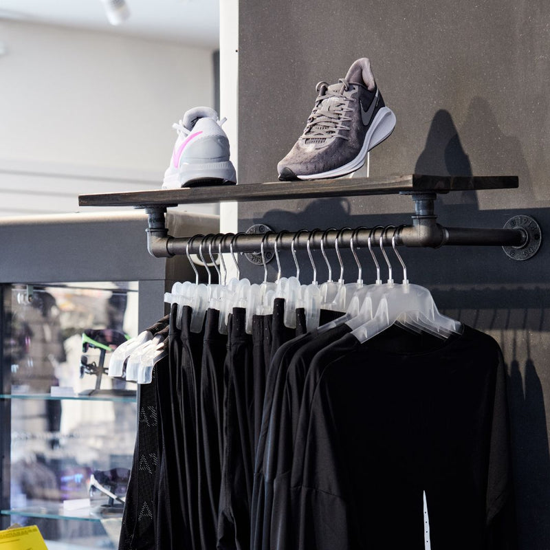 Wall mounted display rack in clothes store with strong iron rail made from water pipes and wooden shelf on top