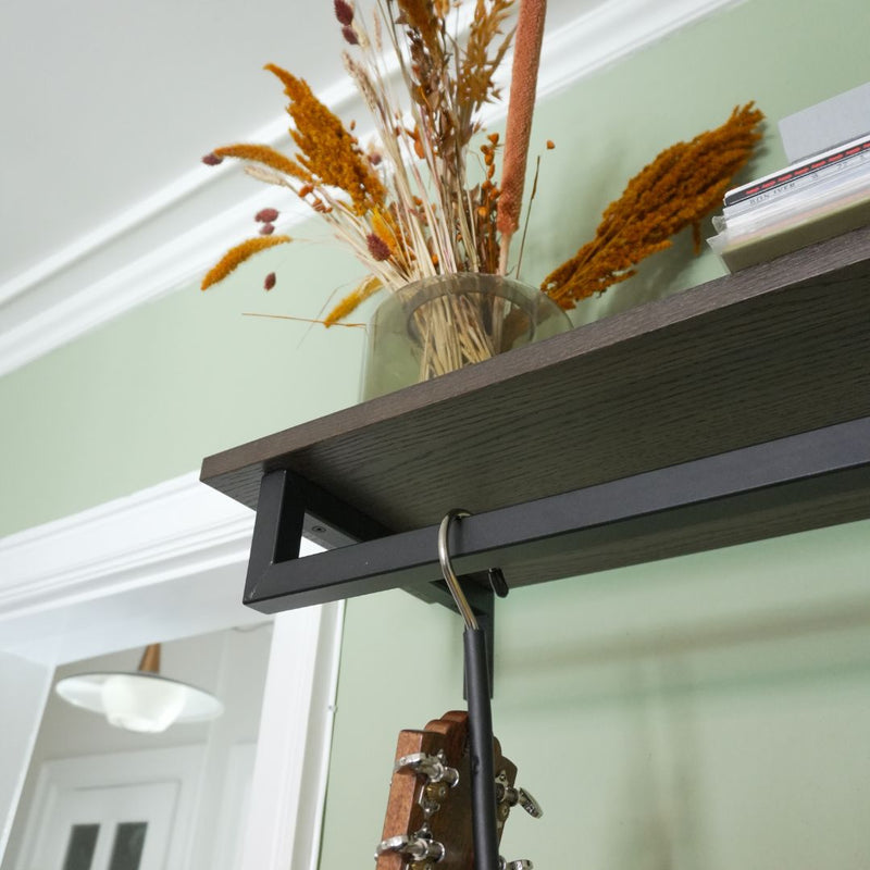 Square black rail used to hang guitars on the wall with smoked oak shelf on the top for decoration