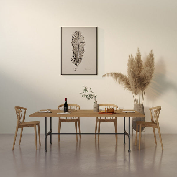 Hell beiger Raum mit Holztisch, vier Stühlen, Pflanzenarrangement und Bild einer Feder an der Wand