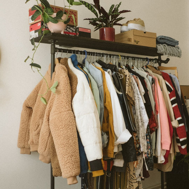 Free standing rack made from stable iron pipes with a lot of space for hanging clothes and a hook and wooden shelf on top