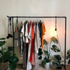 free standing dark pipe racks to hang clothes on hangers, with modern light fixture and hook for camera