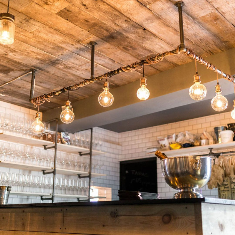 Rustic bar or kitchen design with light fixtures on the ceiling made from dark water pipes