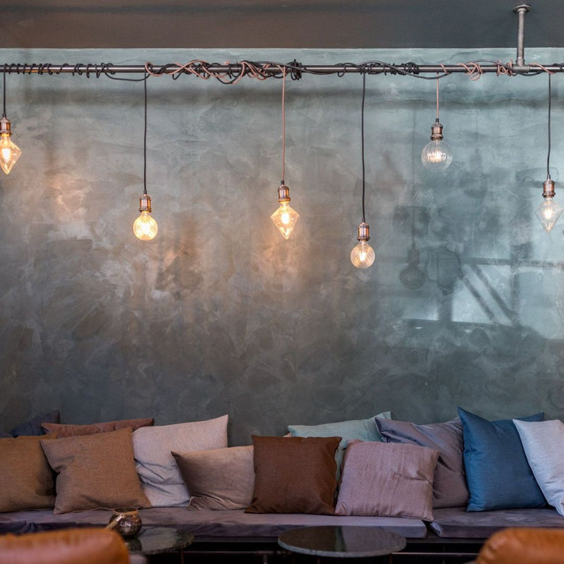 Cozy bar interior design with dark water pipes attached to ceiling used as light fixtures