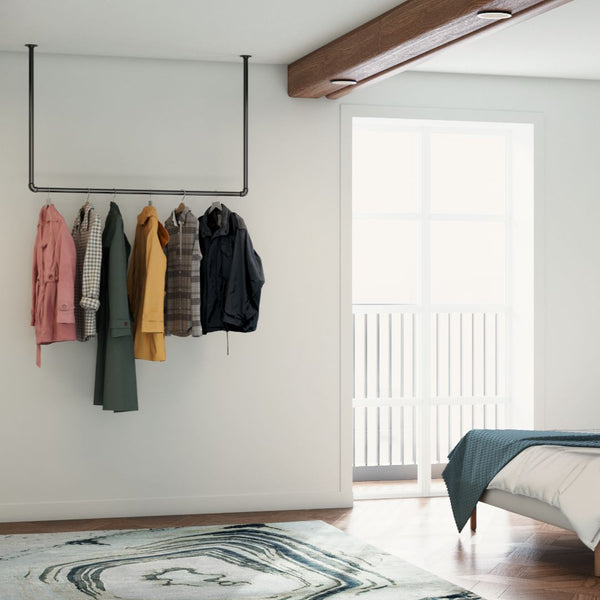 Ceiling mounted clothes rail made from dark iron pipes for open wardrobe in bedroom