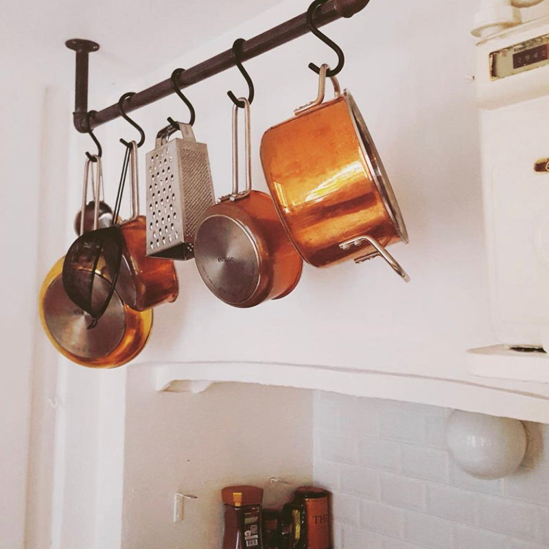 Ceiling mounted rack made from dark water pipes to hang pots pans and sieves in the kitchen