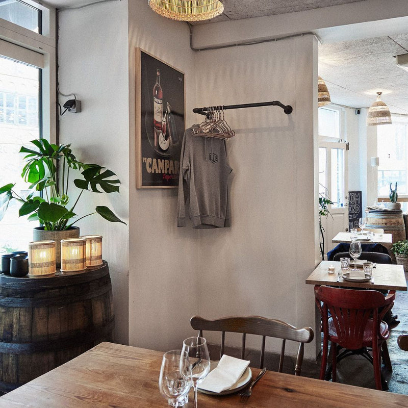 Simple rack made from iron pipes attached to wall in restaurant for jackets and coats