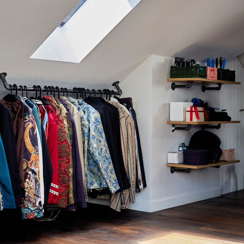 Open closet design in slanted roof room with modern floating shelves attached to the wall