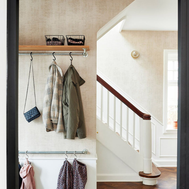 Entrance area interior design simplistic with rail from silver water pipes to hang jackets with hooks