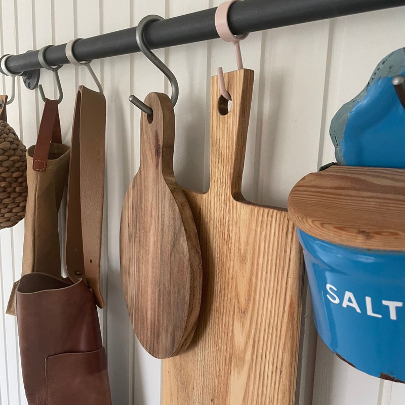 Wall mounted rail with colourful hooks to hang cutting boards and apron in the kitchen