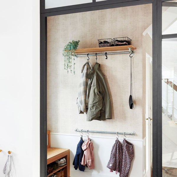 Simple entrance set up with wall mounted clothes rail for jackets and wooden shelf on top