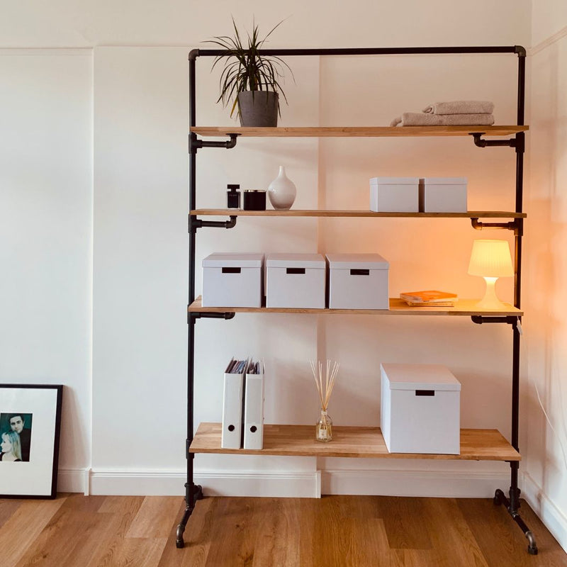 Free standing rack made from iron pipes with multiple wooden shelves for open storage in boxes and decoration